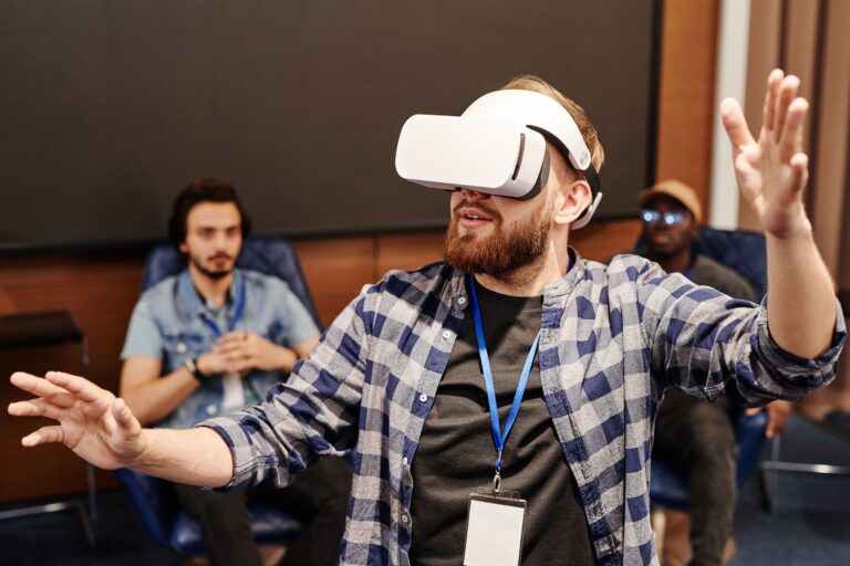 Intelligence artificielle et handicap : un homme porte un casque de réalité virtuelle et bouge les mains, observé par deux personnes.