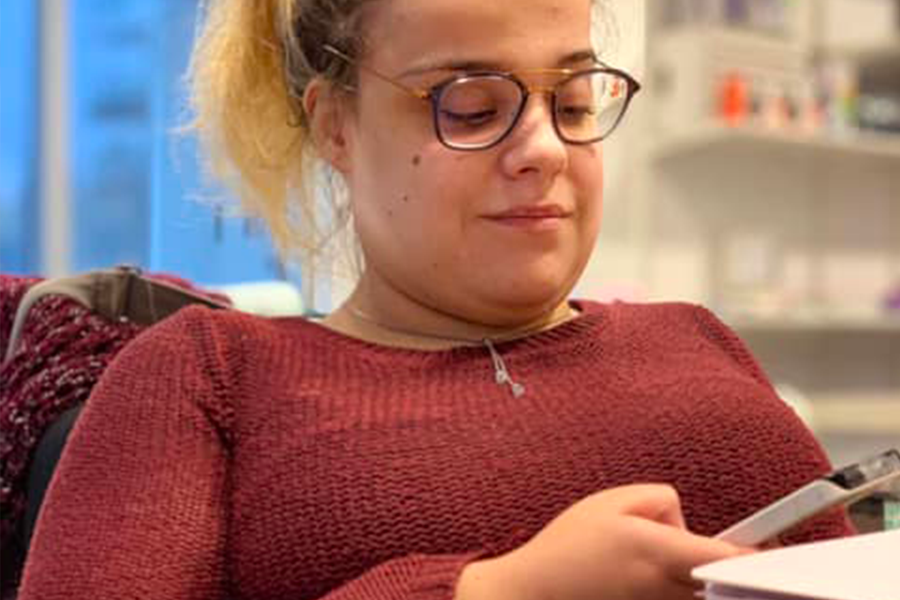Frédérique Cloutier-Fecteau est en fauteuil roulant. Elle regarde son cellulaire. Elle dégage confiance et authenticité.